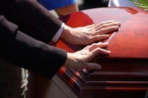 Hands on coffin during funeral prior to burial