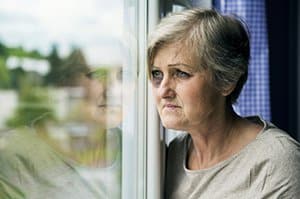Abused elderly woman looking out window