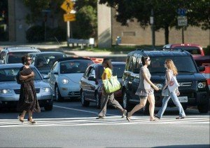 Pedestrians walking through crosswalk in front of stopped traffic