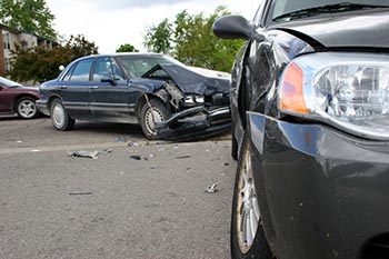 Close up of a car with a smashed front end with wrecked cars in the background