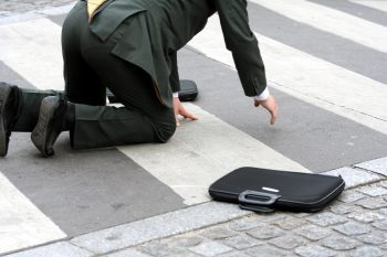 man in suit rising from fall on crosswalk