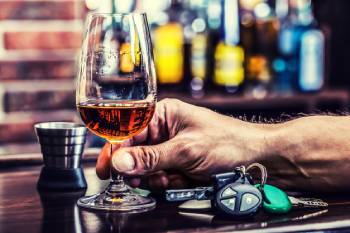 Man holding glass of alcohol next to keys