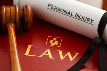 A red law book with a gavel and paper that says personal injury on top