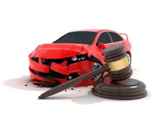 Image of a wrecked red car with a gavel in the foreground