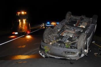 car on its back on highway at night with police in background
