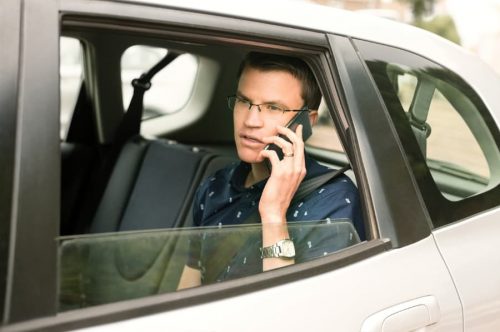 man sitting in backseat on phone