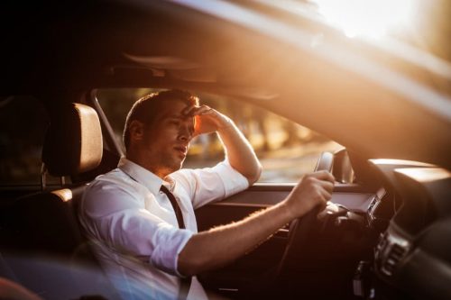 man driving a car tired