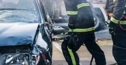 firefighters breaking through a car door with a hydraulic rescue tool