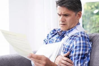 Man in arm sling reading document