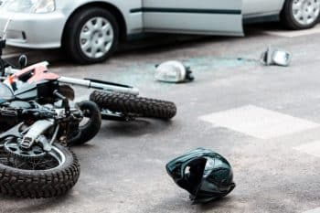 Motorcycle, helmet, and broken glass on the street after collision with a car